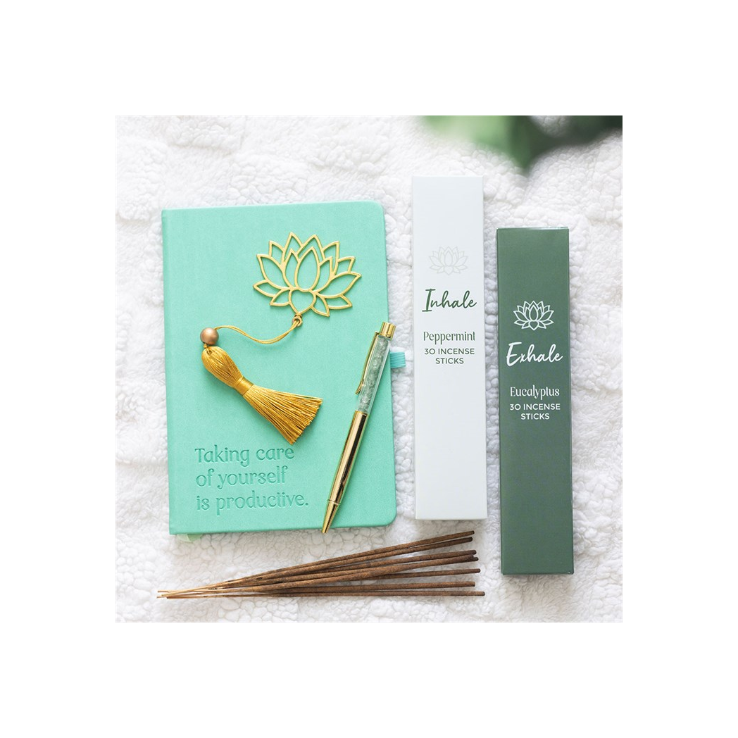 Incense set with a turquoise book, yellow tassel, and incense sticks on a white towel.