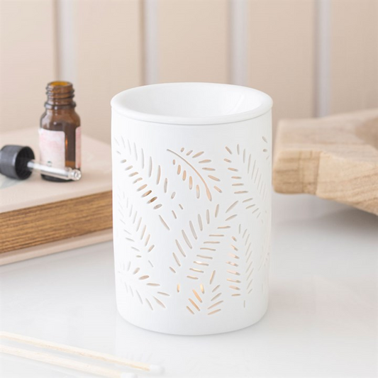 White ceramic diffuser with decorative cut-out design on a light surface.