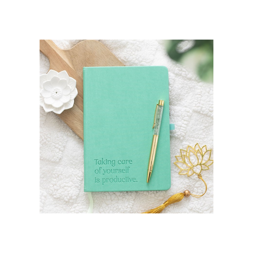 Mint green notebook with a pen on a textured surface with decorative elements.