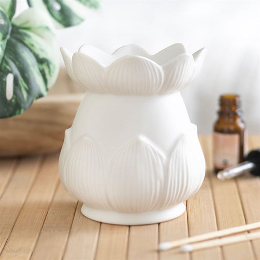 White lotus-shaped oil burner on a wooden surface with a blurred background