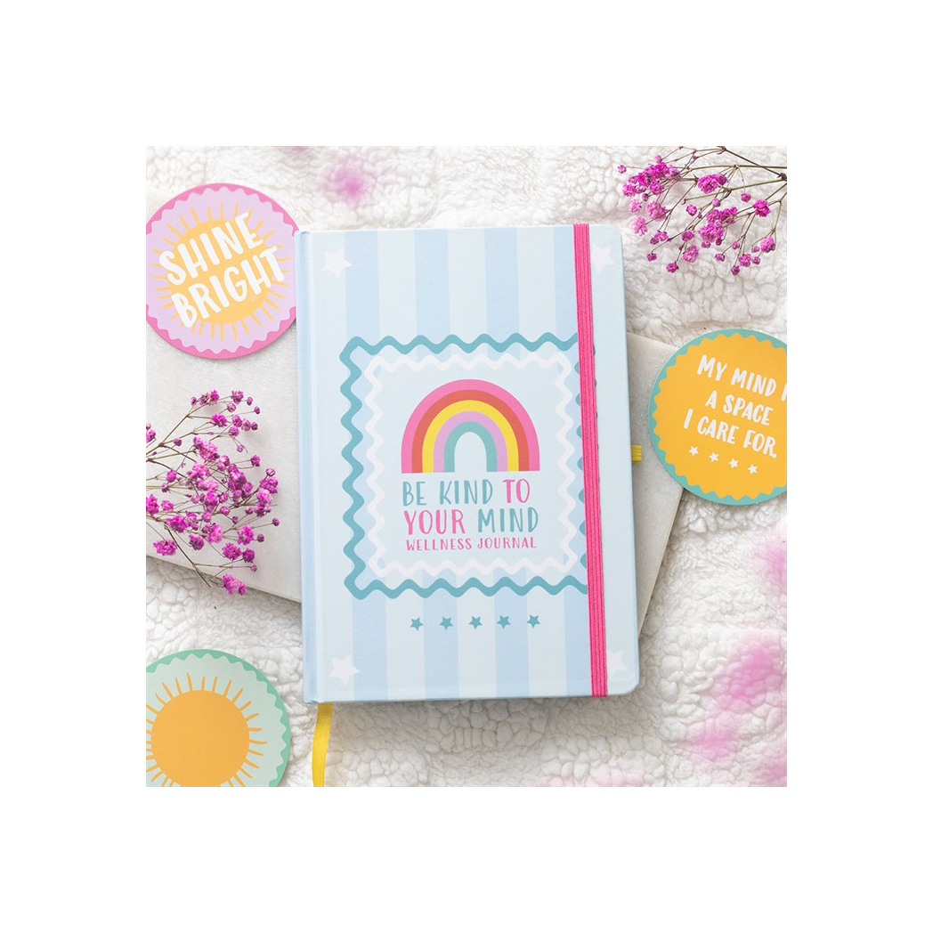 Journal with rainbow design and motivational text on a soft surface with decorative elements.