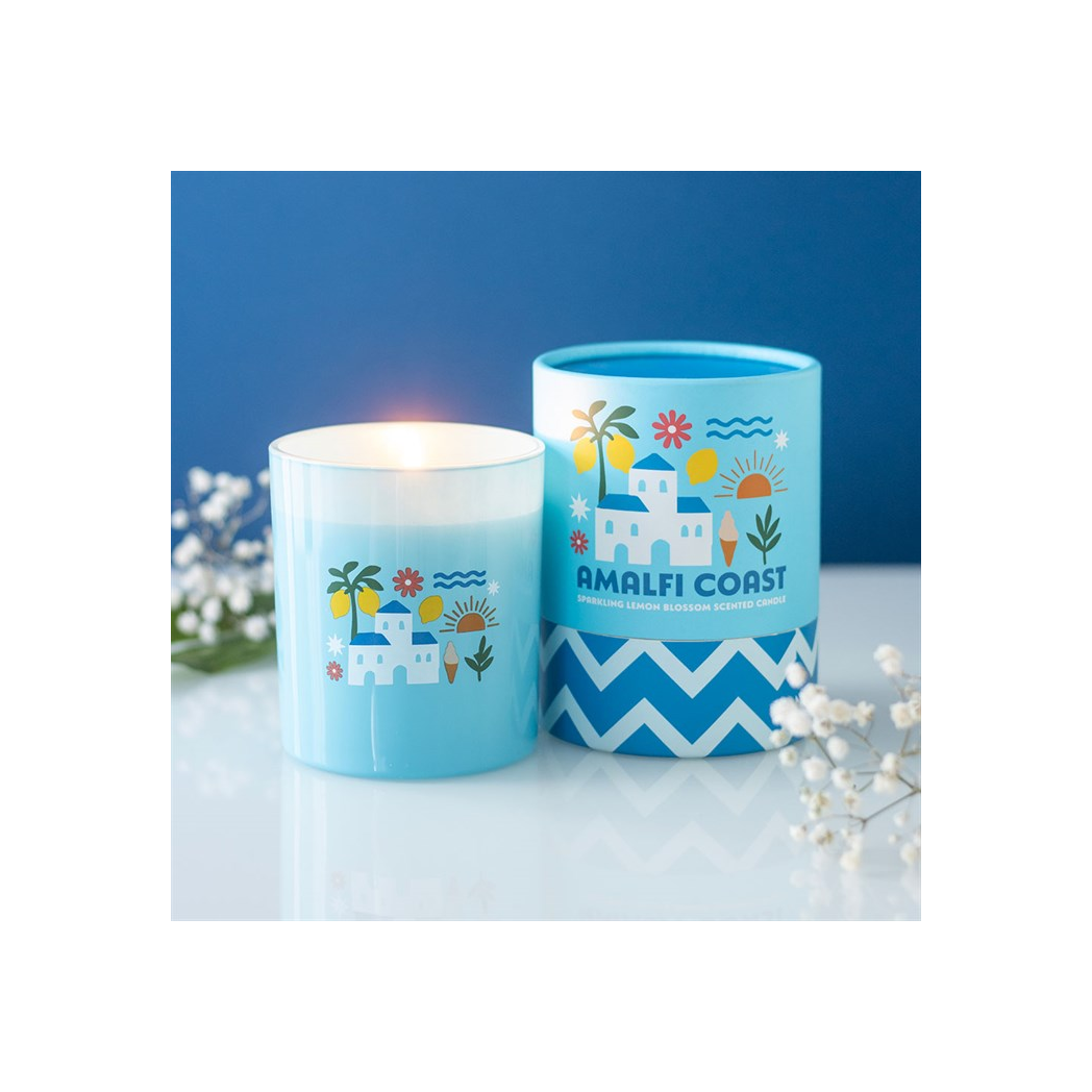 Two blue candles with 'Amalfi Coast' design on a white surface with a blue background