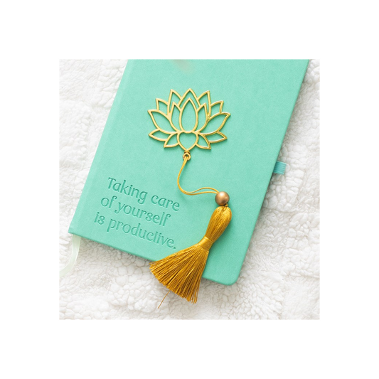 Green notebook with a gold lotus design and tassel on a white textured surface