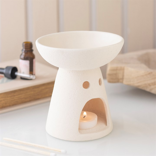 White ceramic diffuser with a candle inside on a light surface.