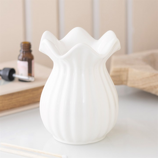 White ceramic pleated oil burner on a light surface with a neutral background